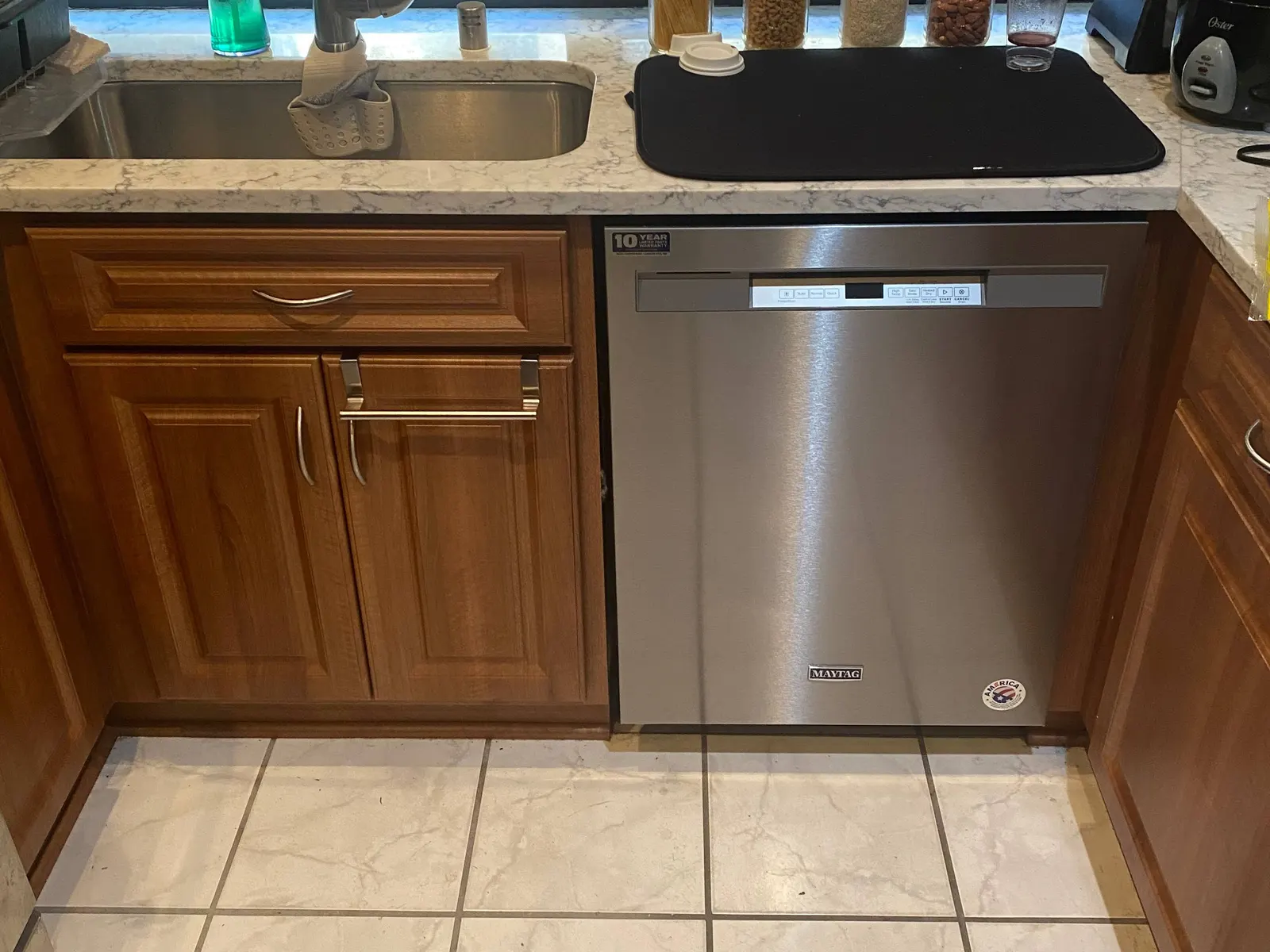 Stainless steel dishwasher installed between wood kitchen cabinets