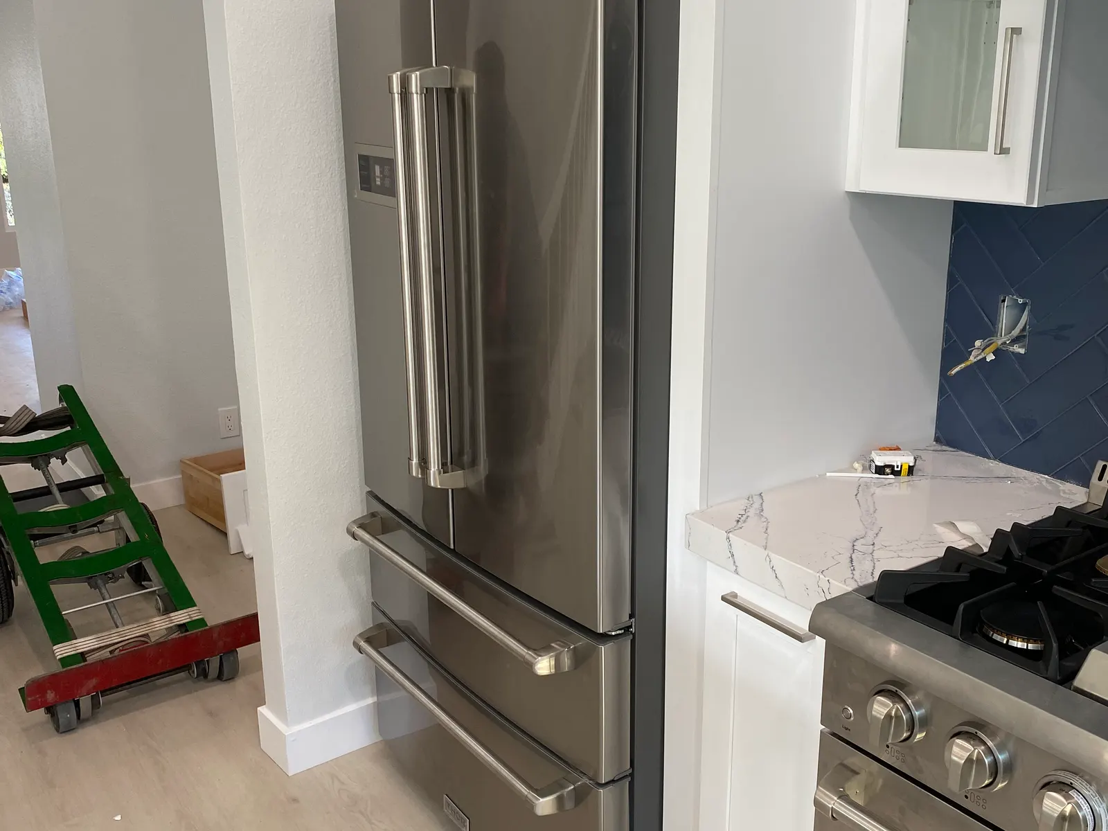 Stainless French-door refrigerator installed beside a range
