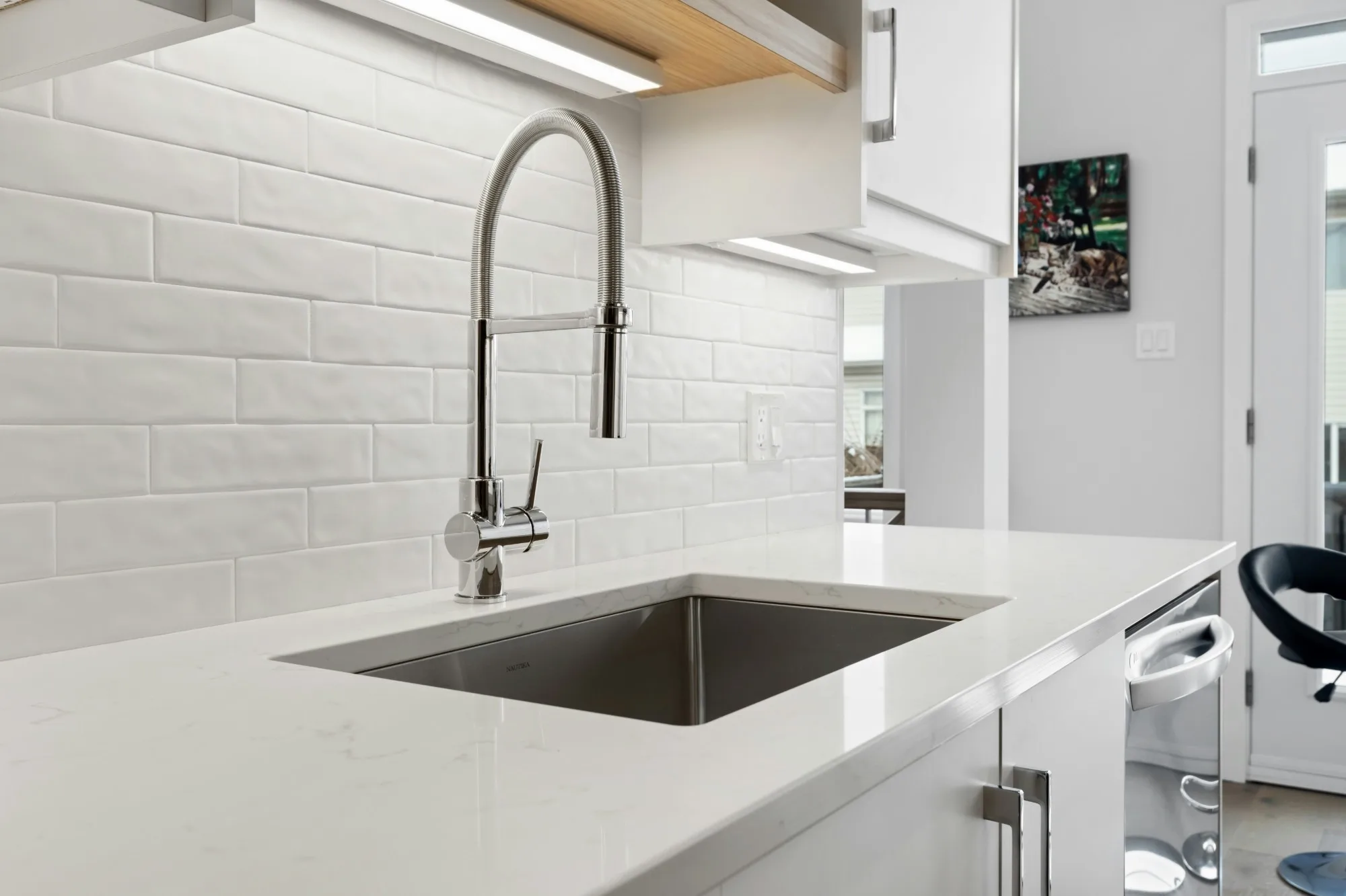 Kitchen sink with a chrome pull-down faucet, white subway tile and a quartz counter